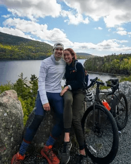 Shannon and Cole with a bicycle overlooking a lake